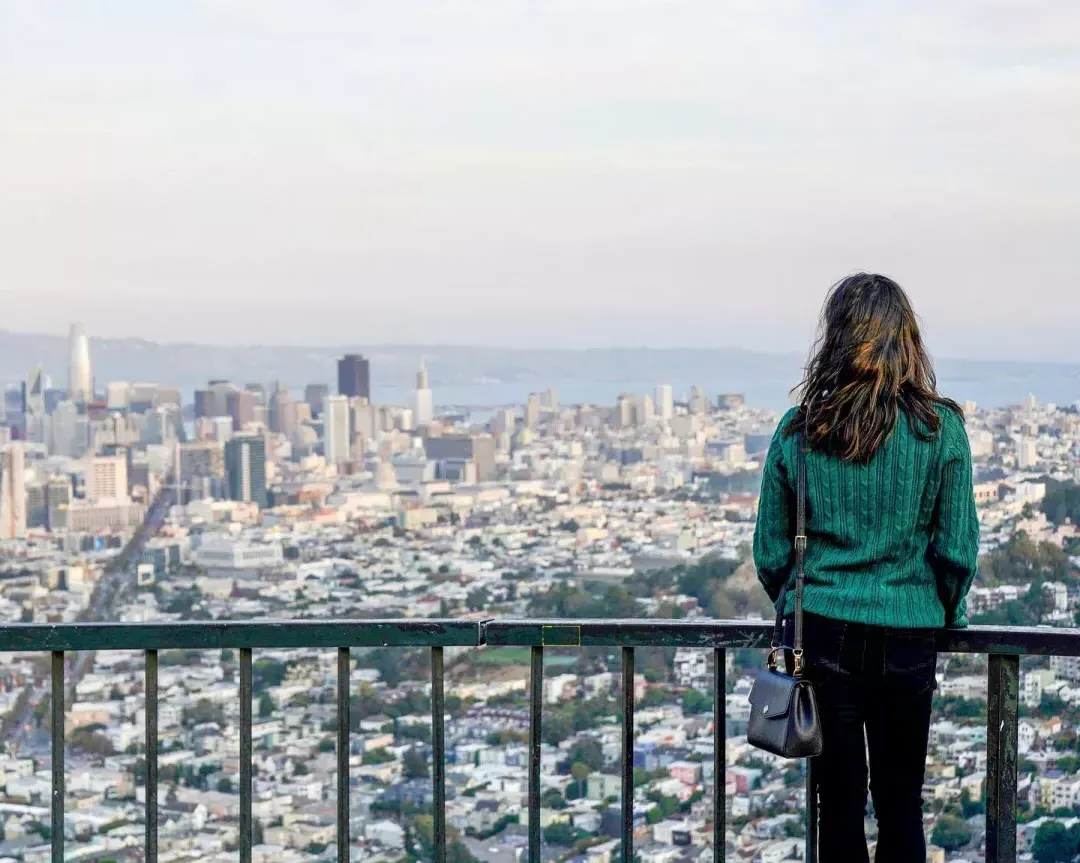 A woman looks at the San Francisco skyline from twin peaks.