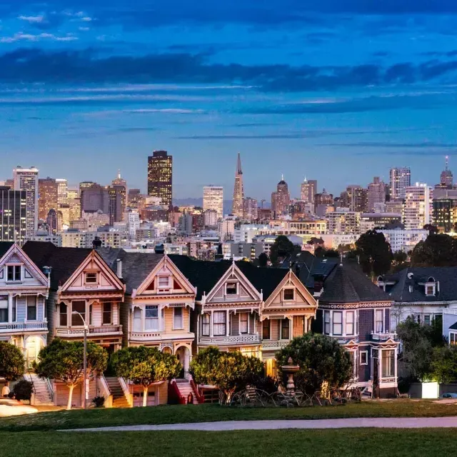 Le famose Painted女士 di Alamo Square sono ritratte di fronte allo skyline di 贝博体彩app al tramonto.